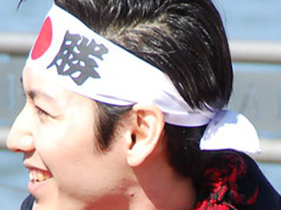 Un homme porte un hachimaki, bandeau représentant le drapeau japonais et un mot ou citation, ici victoire.