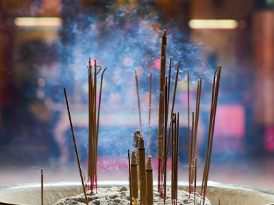 Plusieurs bâtons d'encens brûlent dans un pot au centre d'un temple.