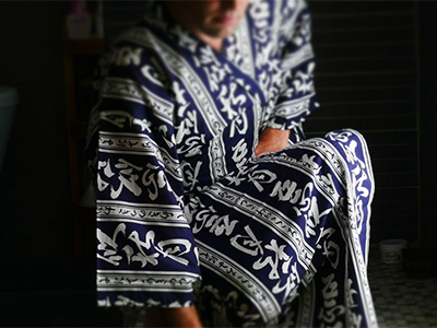 Un homme porte un Kimono avec de larges bandes bleu et de petite bande blanche sur lesquelles sont inscrit des Kanji.
